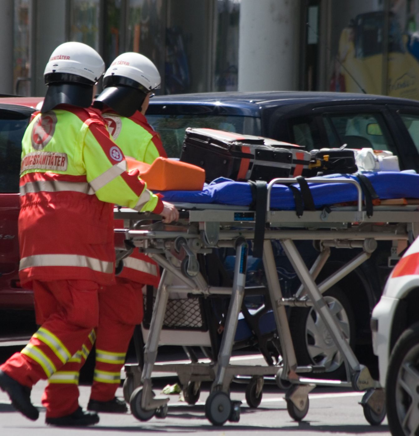 2 Rettungssanitäter in Uniform schieben eine Rettungstrage auf einer Straße