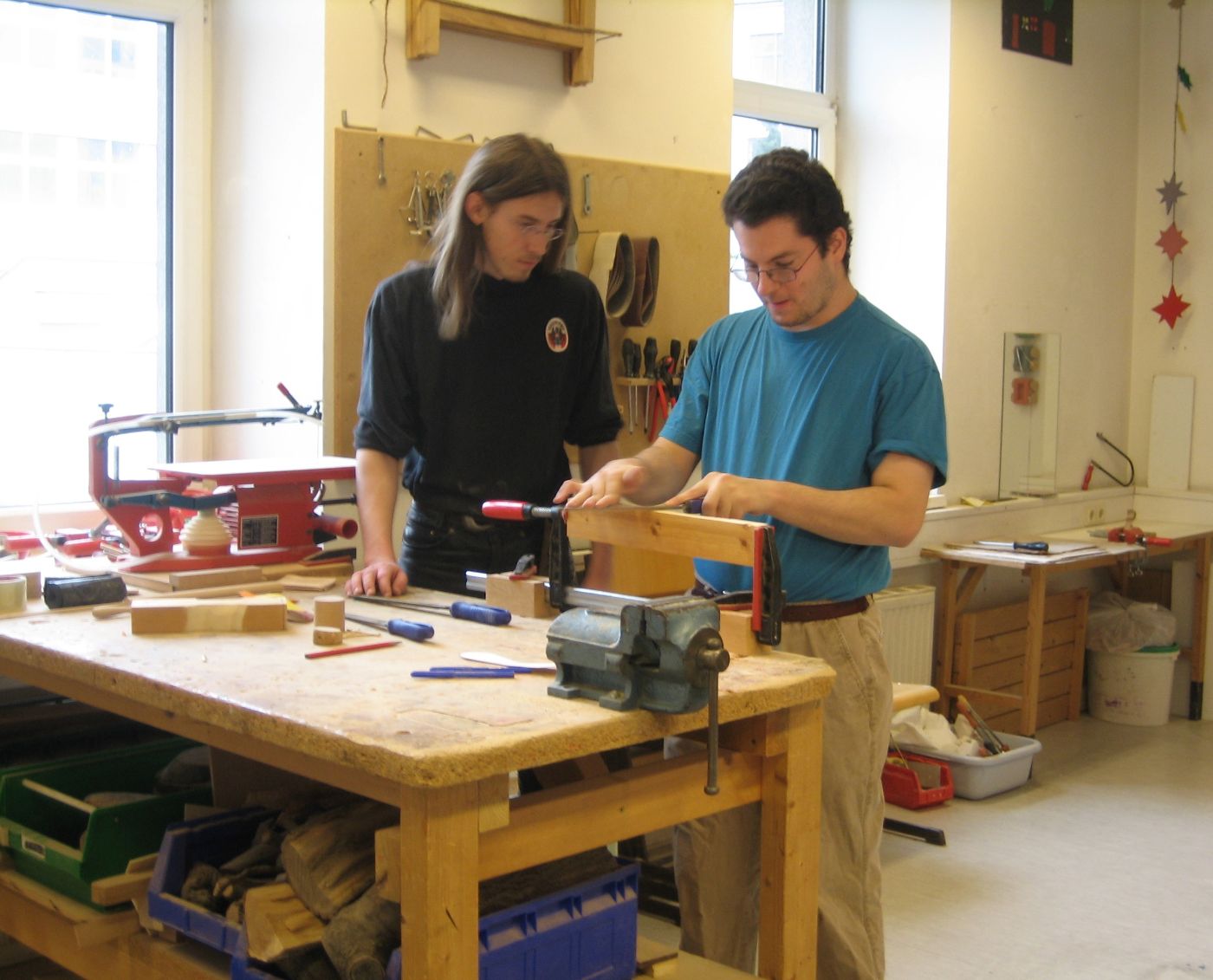 Ein Zivildiener und ein Klient in einer Werkstätte bei der Herstellung eines Werkstückes aus Holz