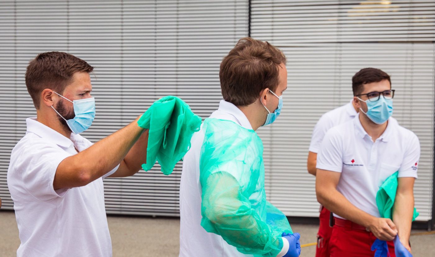 Drei Zivildiener des Österreichischen Roten Kreuzes Vorarlberg beim Anlegen von Schutzkleidung