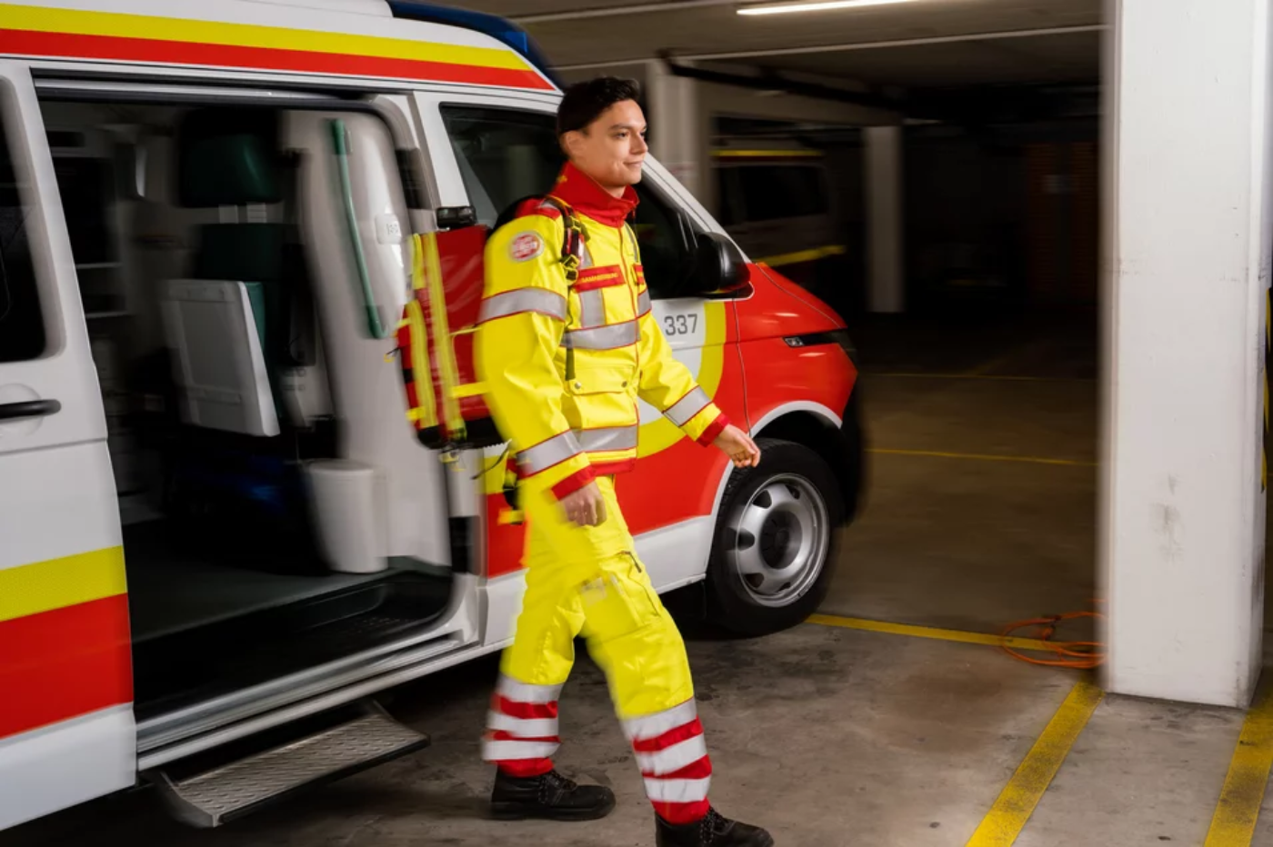 Ein Zivildiener in Uniform des Samariterbundes Österreichs ist aus einem Rettungswagen ausgestiegen, er geht vom Rettungswagen weg, im Hintergrund ist der Rettungswagen zu sehen