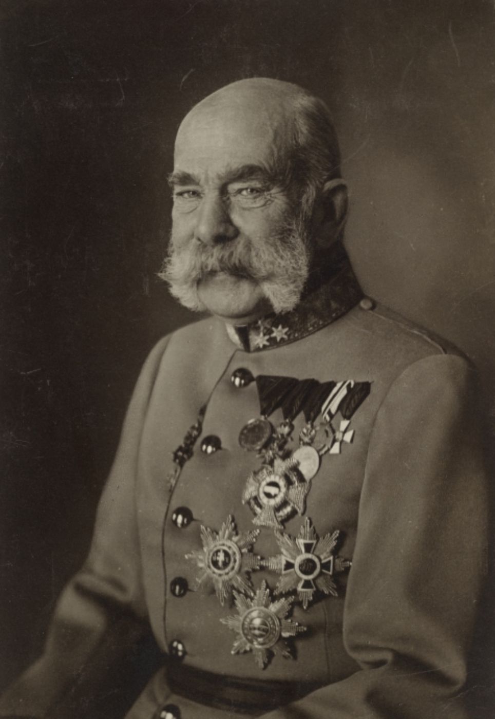Schwarz-weiß-Portrait von Kaiser Franz Josef zur Illustration; Der Kaiser hat einen buschigen grau-weißen Bart, er trägt eine Uniform mit vielen Orden.