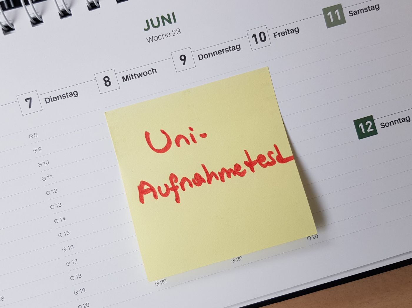 Foto eines Kalenderblattes mit einem gelben Post-It, auf dem in roter Schrift Uniaufnahmeprüfung steht