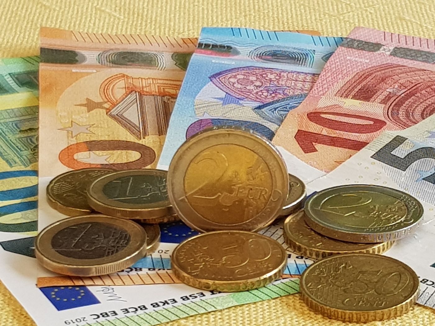 Geldscheine von 5 Euro bis 100 Euro und Münzen liegen aufeinander und nebeneinander;